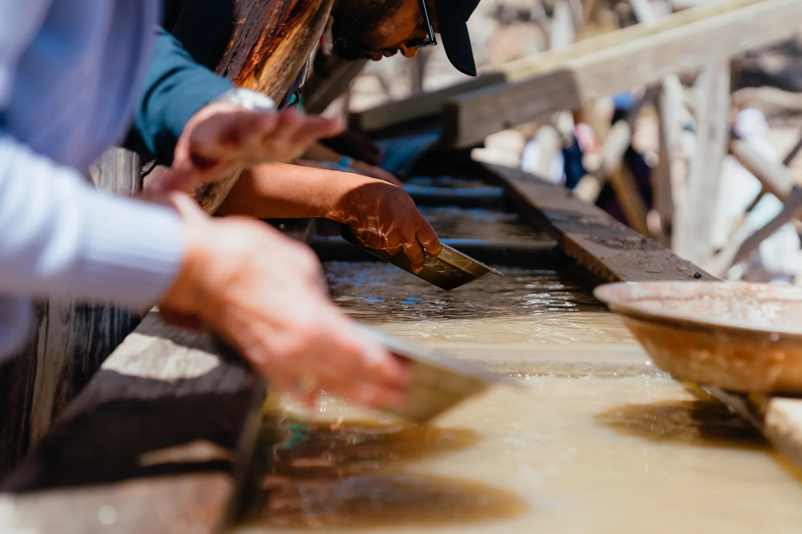 Hands working on wet surface with tools. Close-up of traditional craftsmanship process of gold panning in Ballarat