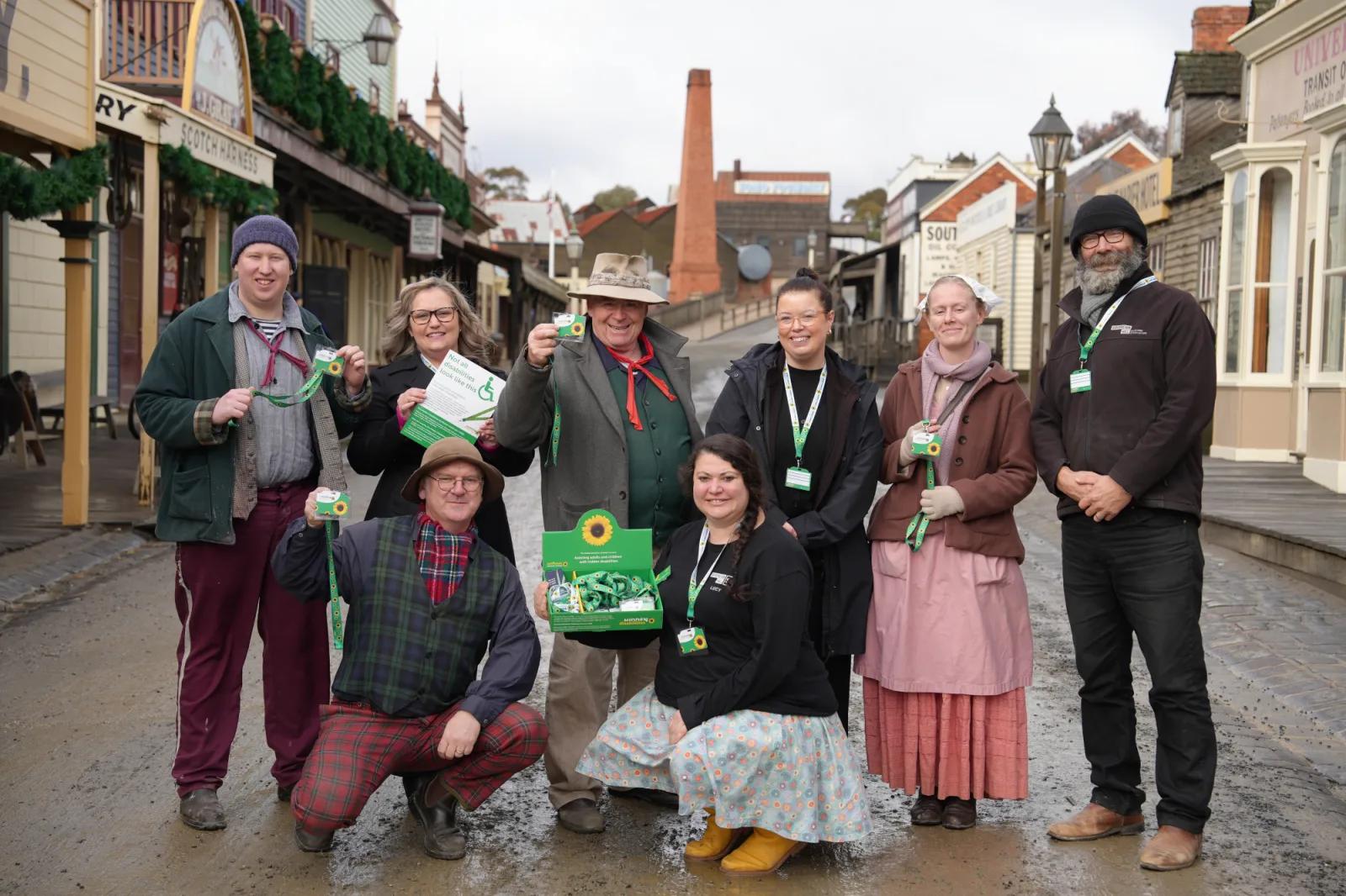 Group of Sovereign Hill staff and volunteers in heritage street wearing sunflower lanyards for accessibility inclusion, from Australia’s most visited outdoor museum and heritage attraction.