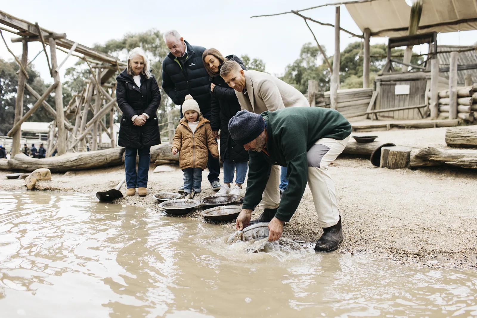 A family enjoys gold panning together at Sovereign Hill, guided by a costumed interpreter, a fun, hands-on adventure included with the Pioneer Pass Family ticket. Perfect for exploring the gold rush era through immersive, interactive history at Sovereign Hill.