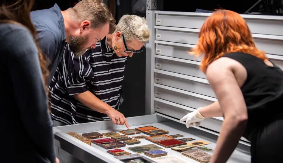 Researchers or curators inspecting a curated selection of historical documents, textiles, or decorative objects from Sovereign Hill's material archive.
