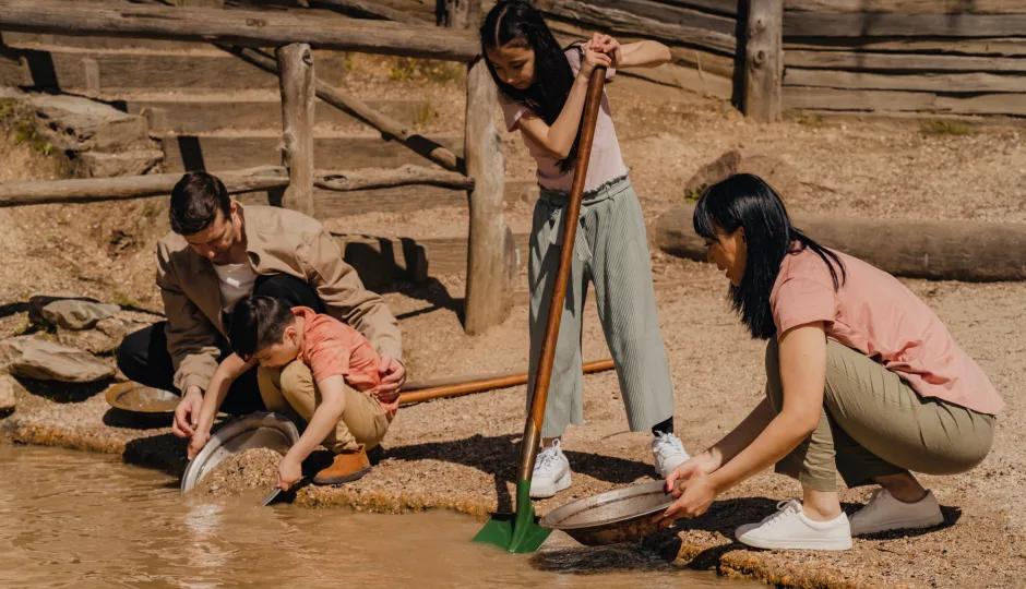 Visitors engaging in the gold panning activity at an outdoor historical site, learning about gold extraction in Sovereign Hill