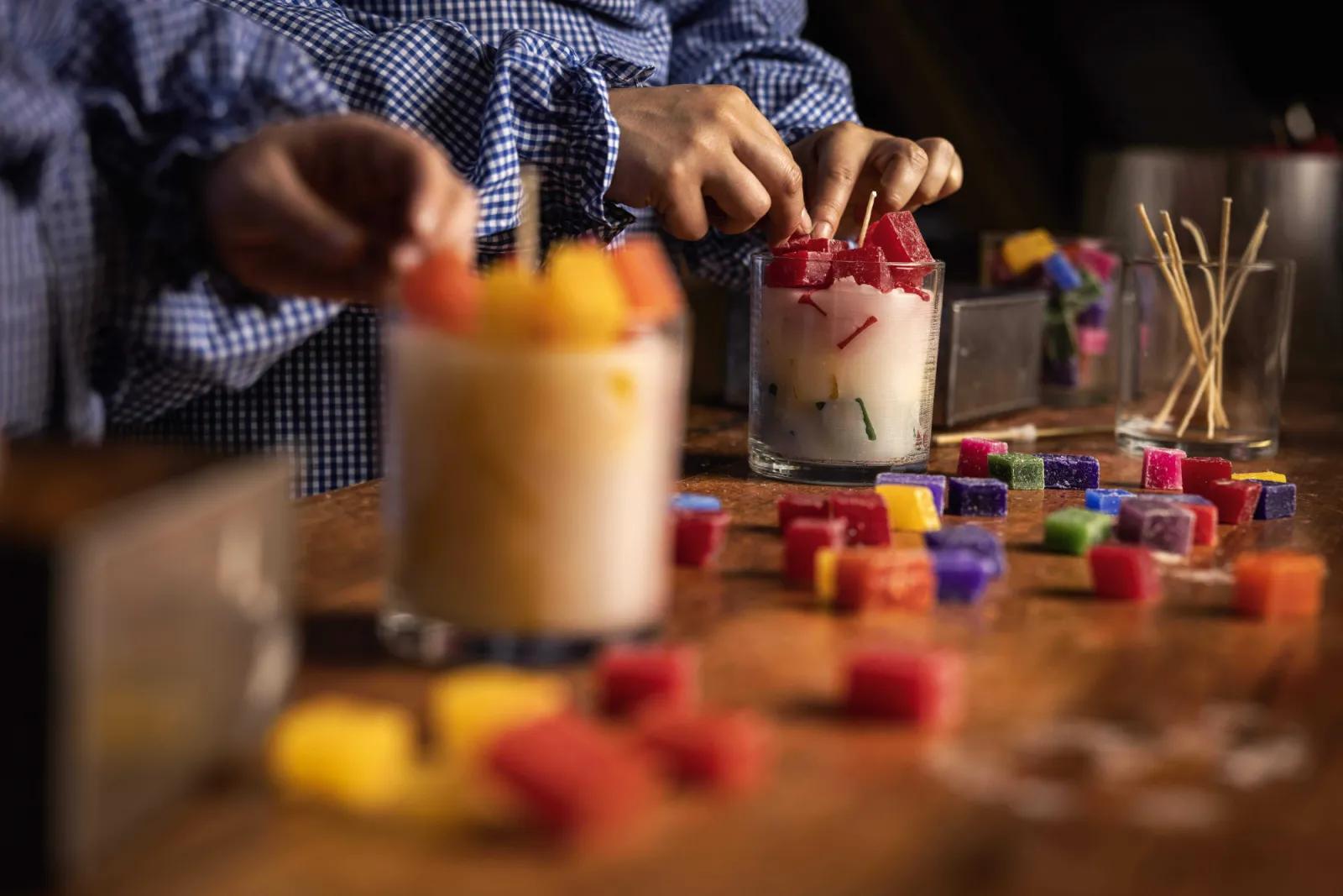 Someone making artistic layered candles with colorful wax cubes at Sovereign Hill