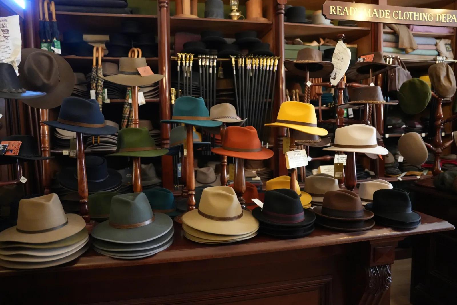 Colourful felt hats displayed on wooden stands and shelves inside Sovereign Hill’s historic ready-made clothing store.