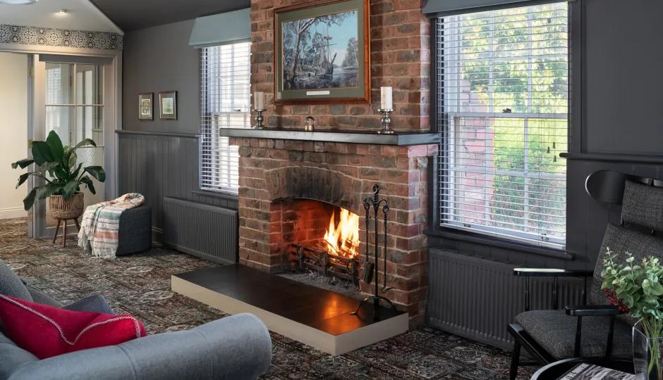 Warm heritage lounge room with fireplace, armchairs, and historic décor, from Australia’s most visited outdoor museum and heritage attraction.
