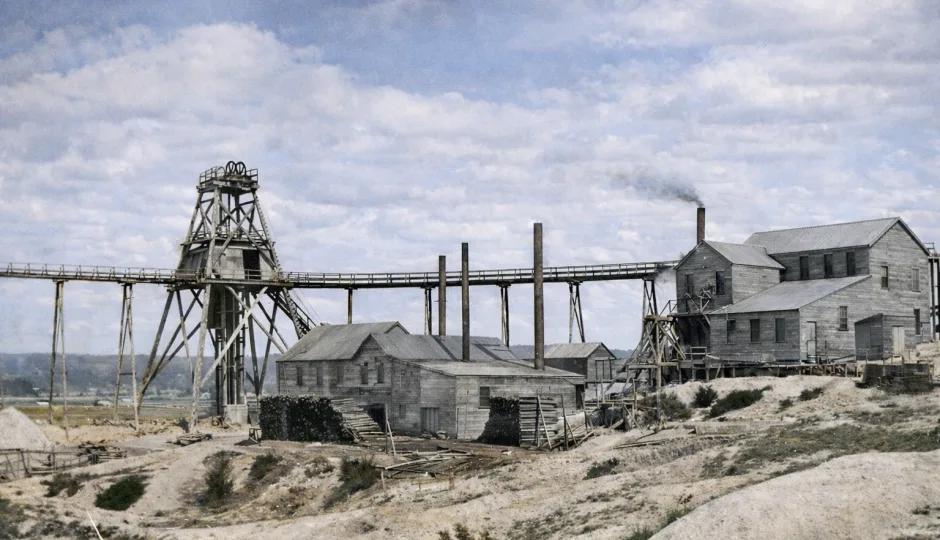 Colourised historic photograph of North Normanby Mine showing its timber headframe, elevated conveyor, chimneys and industrial buildings.