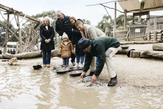 A family enjoys gold panning together at Sovereign Hill, guided by a costumed interpreter, a fun, hands-on adventure included with the Pioneer Pass Family ticket. Perfect for exploring the gold rush era through immersive, interactive history at Sovereign Hill.